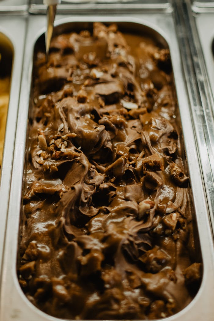Rich chocolate ice cream with nuts, captured in a metal tray for a gourmet appeal.