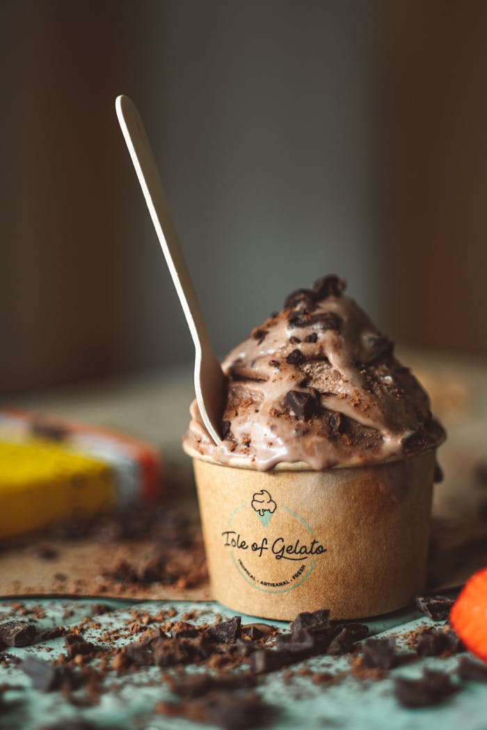 Close-up of chocolate gelato in a branded cup with a spoon, perfect for dessert lovers.